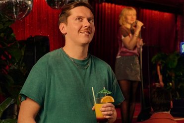 Junger Mann mit Drink im Club