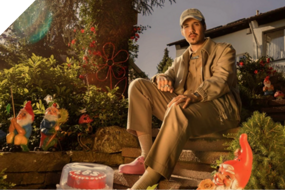 Rapper sitzt mit Gartenzwerg auf der Treppe in seinem Garten
