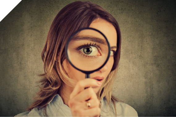 Frau schaut durch eine Lupe