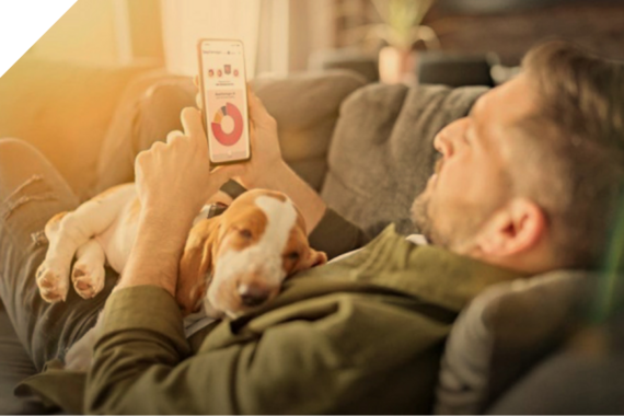 Mann liegt mit seinem Hund auf dem Sofa und schaut in die S-App