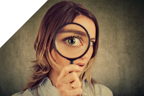 Frau schaut durch eine Lupe