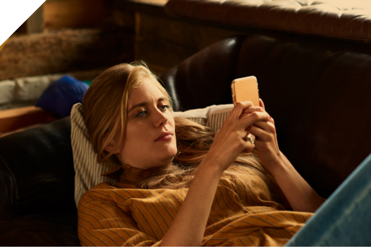 Person liegt mit Handy auf dem Sofa