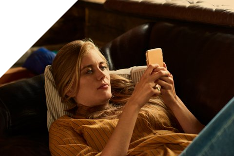 Person liegt mit Handy auf dem Sofa