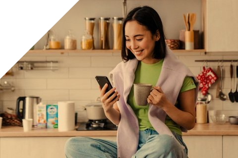 Mädchen sitzt auf dem Küchentisch und schaut ins Handy