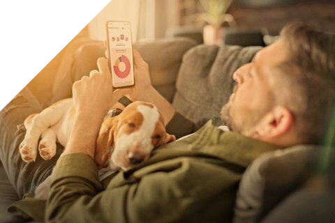 Mann liegt mit seinem Hund auf dem Sofa und schaut in die S-App